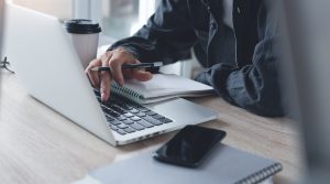 Man with Laptop & Mobile Device Reviewing Marketing Strategy